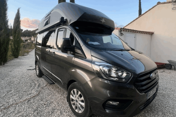 Fourgon aménagé gris stationné en extérieur au crépuscule